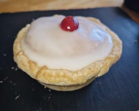 A freshly baked pie with a glazed top and a cherry on top.