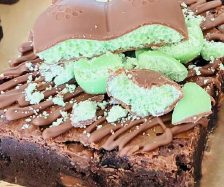Brownie topped with mint chocolate pieces and green fondant, sprinkled with chocolate shards.