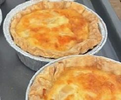 Two golden-brown baked pies in foil containers.